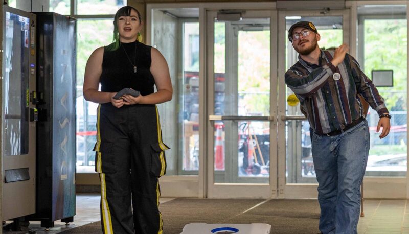 Two students throwing cornhole bags