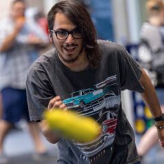 A student throwing a cornhole bag. The bag is visible mid-air.