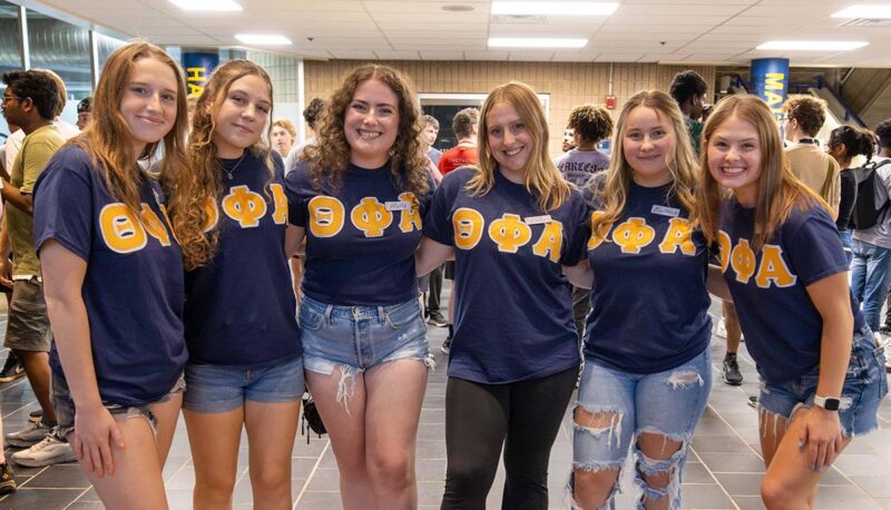 A group of students wearing Theta Phi Alpha shirts.