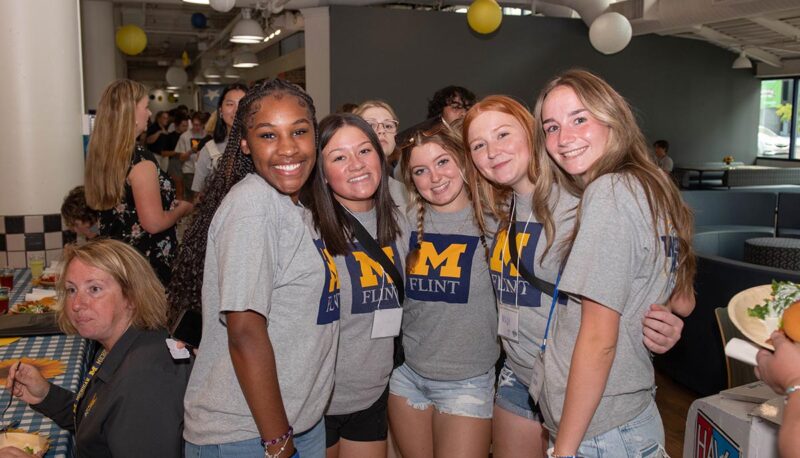 A group of students smiling for the camera inside the University Pavilion.