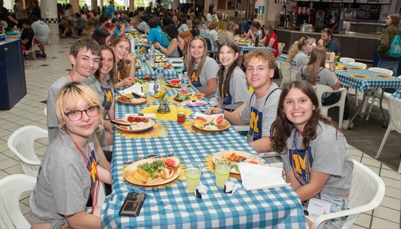 A table of students with food smiling for the camera.