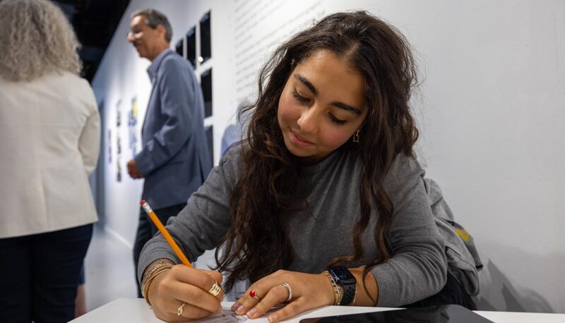 A gallery visitor writing their own memories.