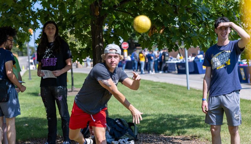 A student throwing a ball at a dunk tank.