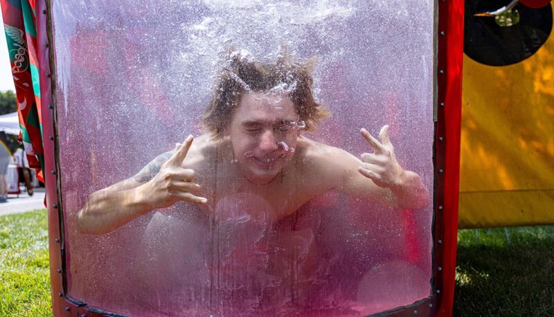 A student giving the "rock on" hand sign underwater in a dunk tank.