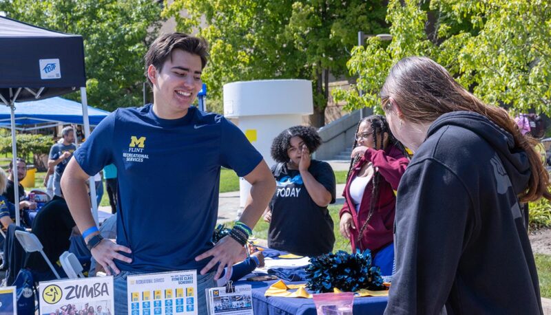 A student talking to other students at a table.