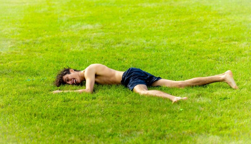 A student laying in the grass on the North Lawn.