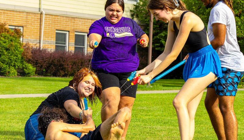 A group of students squirting each other with water guns