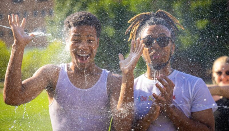 Two students posing for the camera while being splashed.