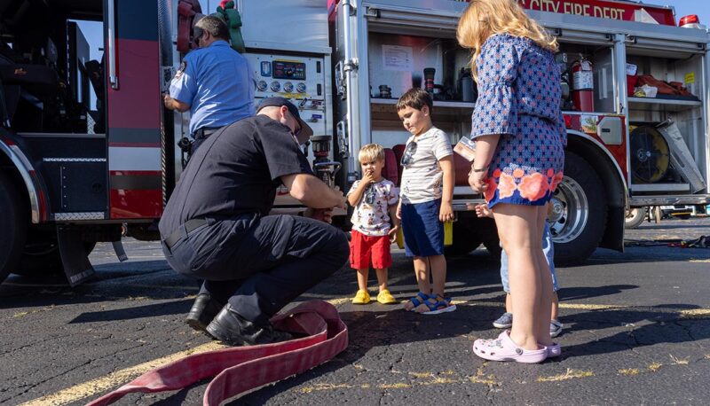 Young children seeing a firehose with a firefighte.r