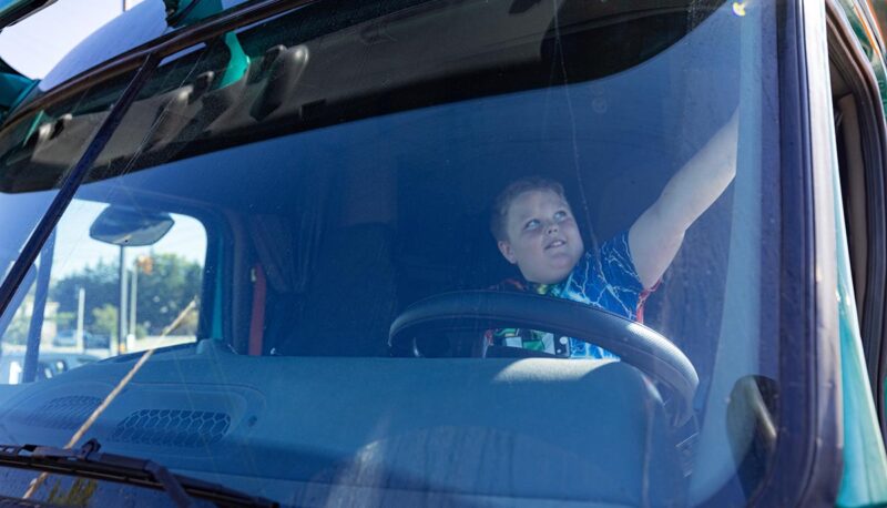 A young child in the driver's seat of a semi truck