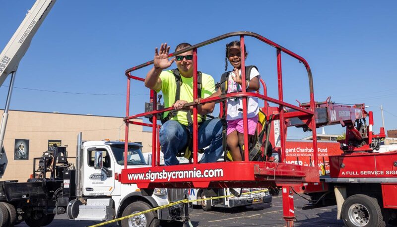 A young child preparing to go up in a cherry picker.