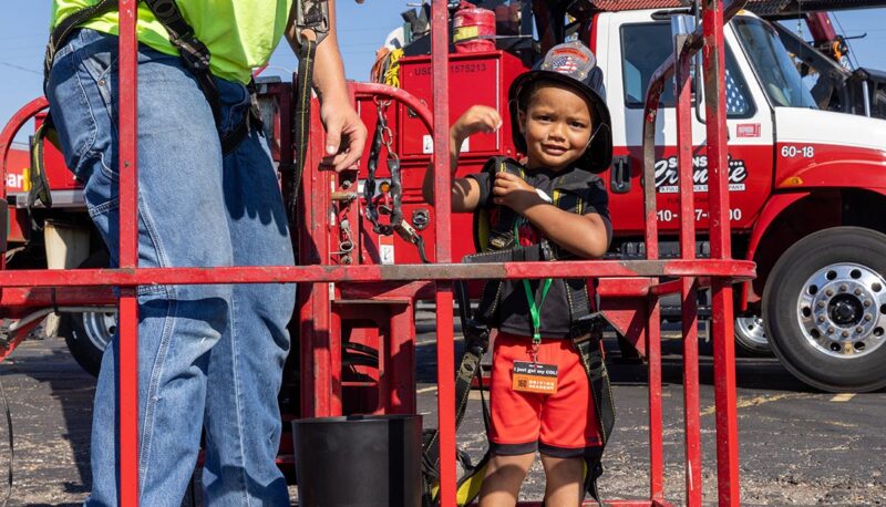 A young child preparing to go up in a cherry picker.