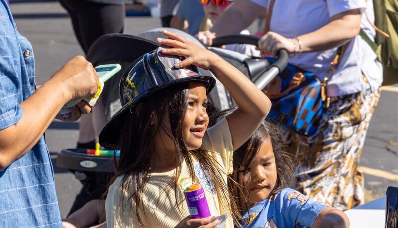 A young child wearing a firefighter helmet