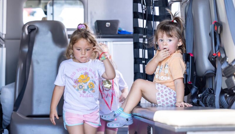 Two young children exploring the back of an ambulance.