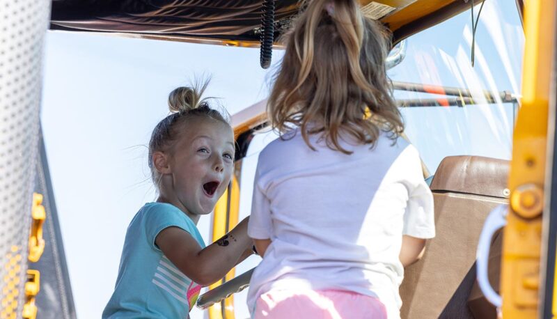 Two young children in the cab of a service truck