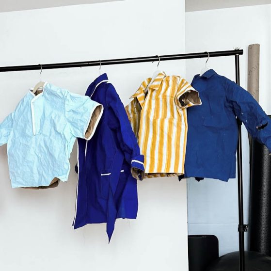 Clothes rack with paper sculptures of four different dress shirts on hangers