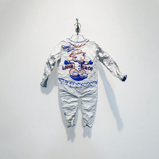 A paper sculpture of a baby's romper with blue and red markings