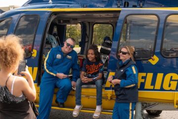 The crew of the Michigan Medicine survival flight helicopter posing with a child and the helicopter.