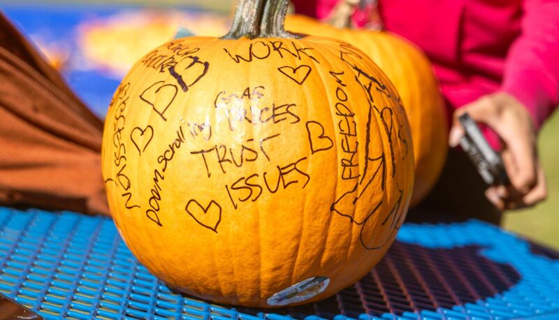 A pumpkin with words written on it waiting to be smashed.