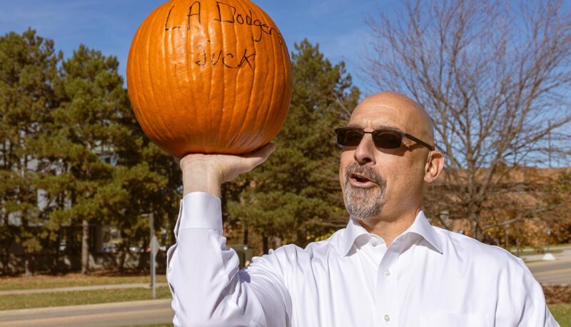 A UM-Flint administrators holding a pumpkin with "LA Dodgers Suck" written on it.