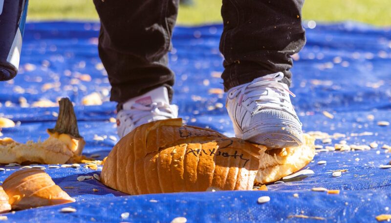 A closeup of a student stomping a pumpkin.