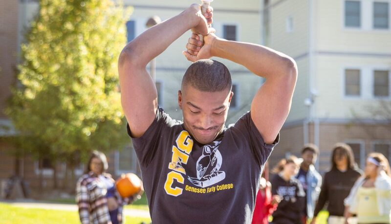 A student smashing pumpkins with a baseball bat.