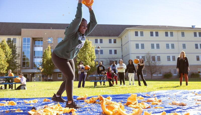 A student throwing a pumpkin on the ground.