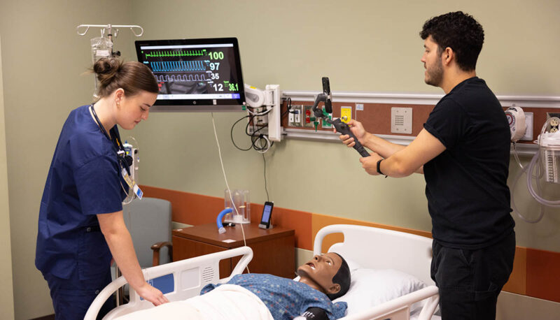 A nursing student attending to a dummy patient while being videotaped