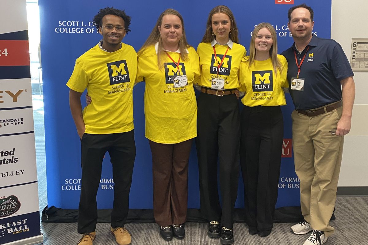 UM-Flint School of Management Marketing Students and Professor Dan Lake pose for a photo in front of the Saginaw Valley State University Regional Sales Competition banner on Oct. 12.