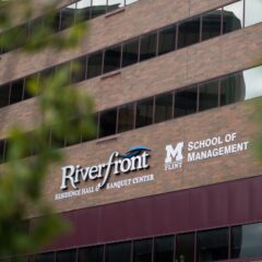 Image of exterior Riverfront Center building with Riverfront Banquet Center and UM-Flint School of Management logos as the focus.