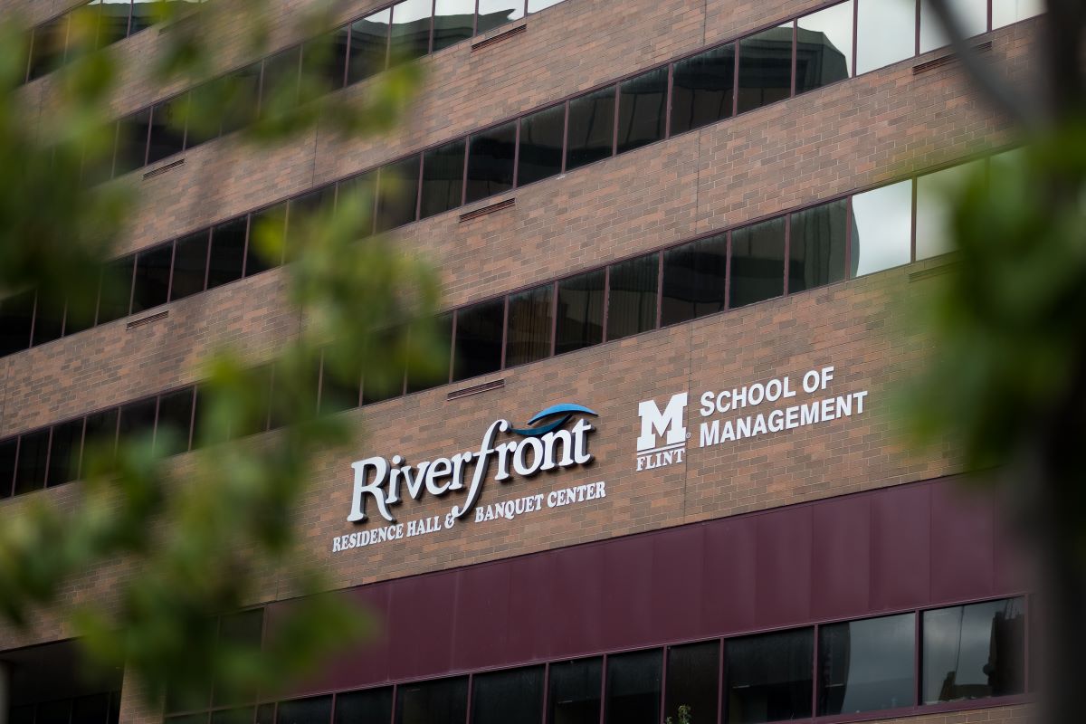 Image of exterior Riverfront Center building with Riverfront Banquet Center and UM-Flint School of Management logos as the focus.