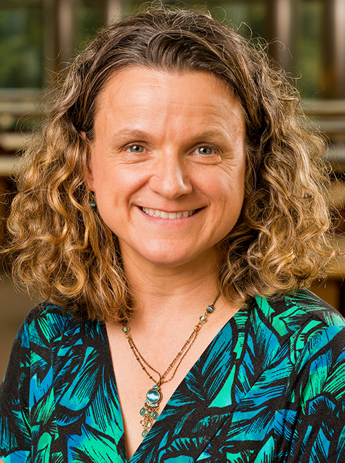 A portrait photograph of Helen Budd taken in a library.