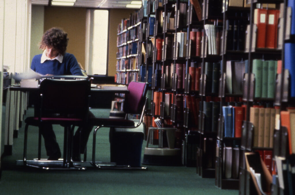 A student studying at a table surrounded by books 