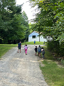 Kids and a camp counselor running on a dirt road in the forest