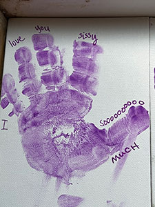 A purple handprint on a canvas created by a child at Camp Hope