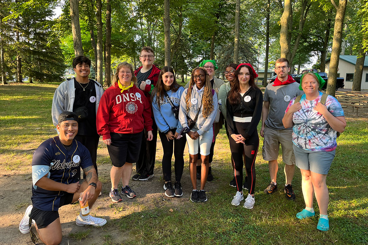 A group of UM-Flint psychology interns posing for the camera with a forest in the background