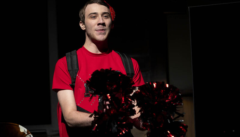 A student actor holding a present on stage