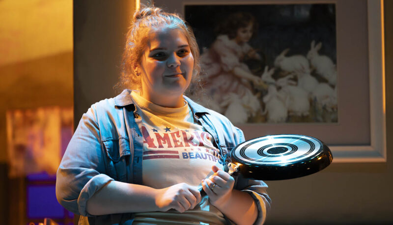 A student actor holding a frying pan