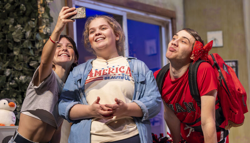 A group of student actors taking a selfie on stage