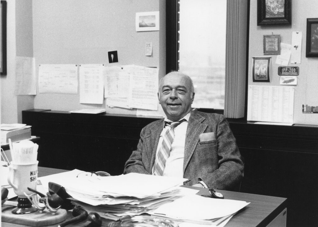 David Palmer in a black and white photo sitting at a desk