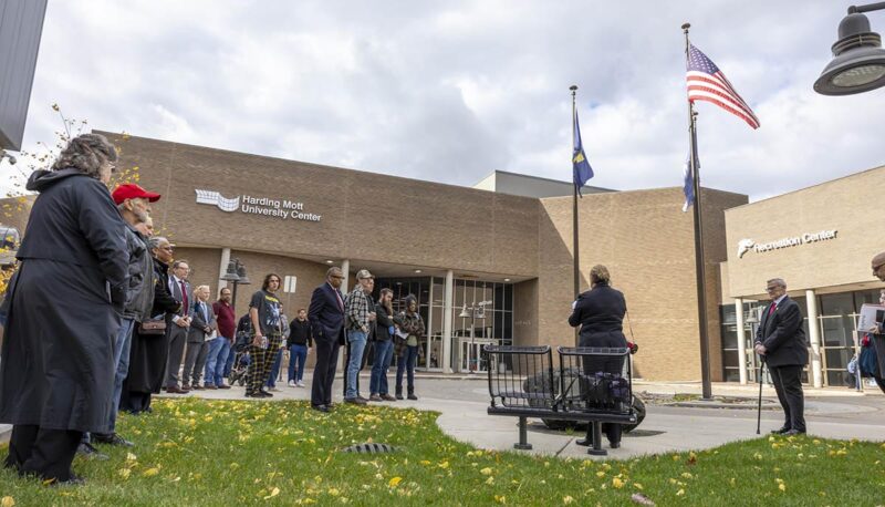 Event attendees standing while a dedication ceremony takes place outside of University Center.