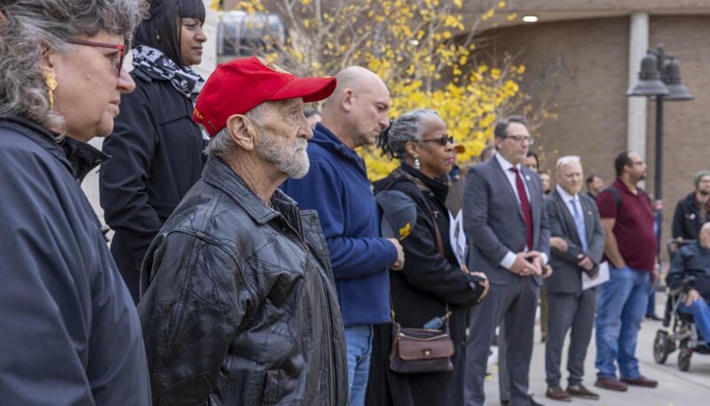 Event attendees standing while a dedication ceremony takes place outside of University Center.