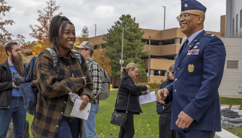 A man in an Air Force dress uniform standing outside talking with event attendees