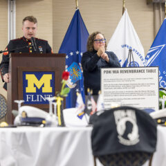 A speaker in a Marine Corps dress uniform speaking at a podium