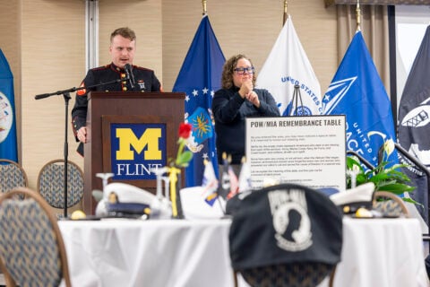 A speaker in a Marine Corps dress uniform speaking at a podium
