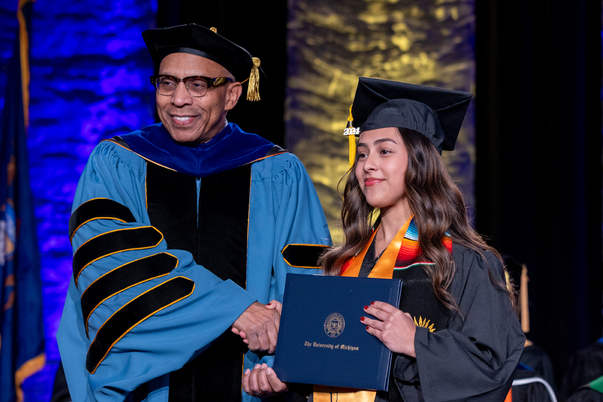 Chancellor Alexander shakes hands with a UM-Flint graduate