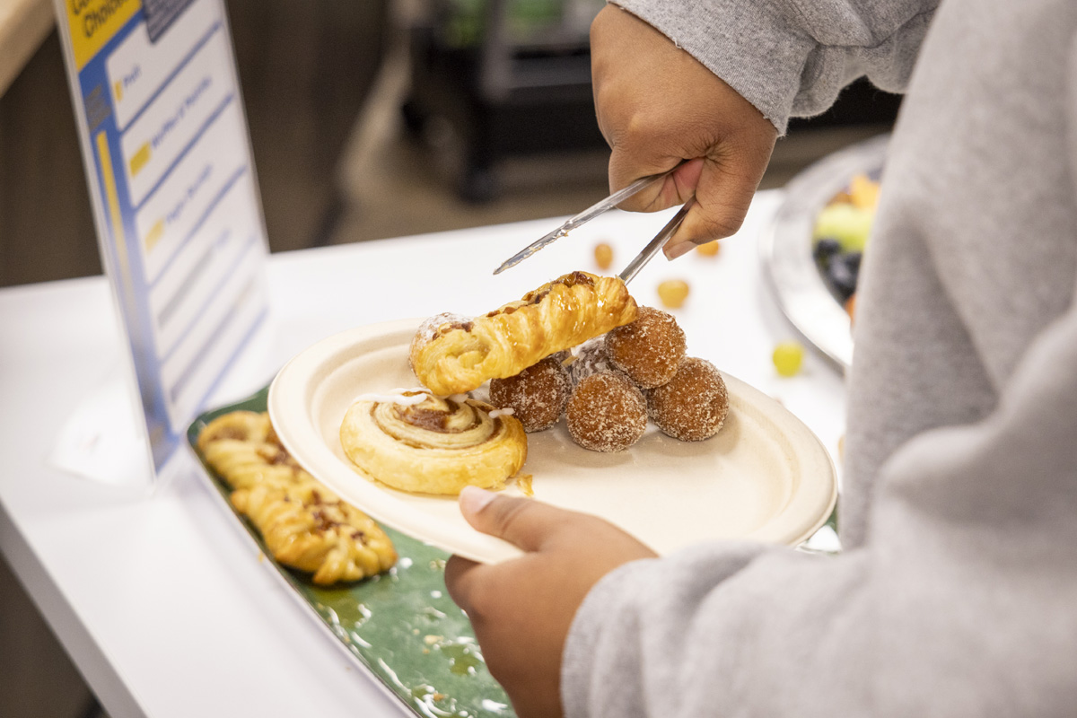 A person places a pastry on a plate filled with doughnut holes and a cinnamon roll.