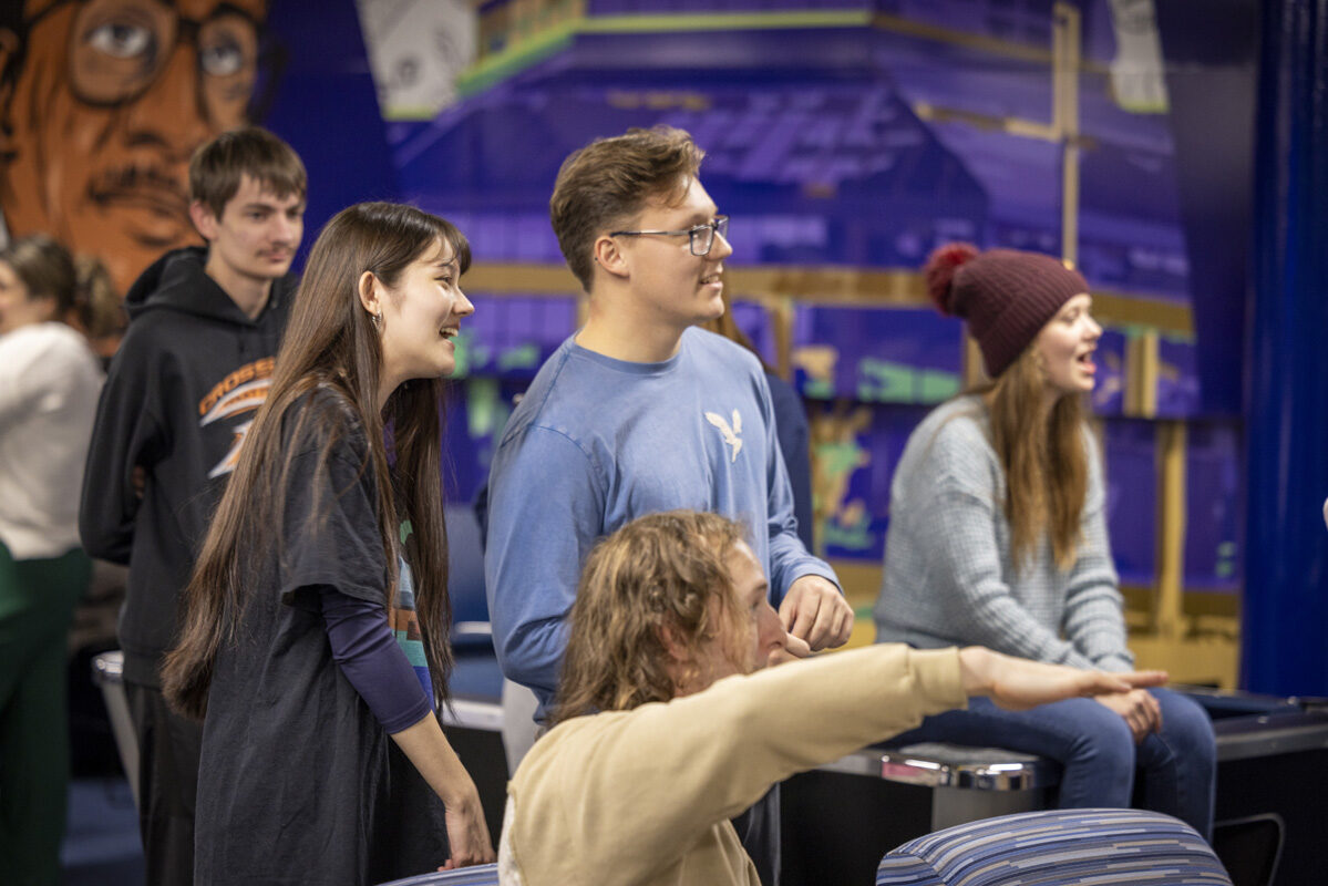 A group of young adults laughing and pointing in a colorful recreational area.