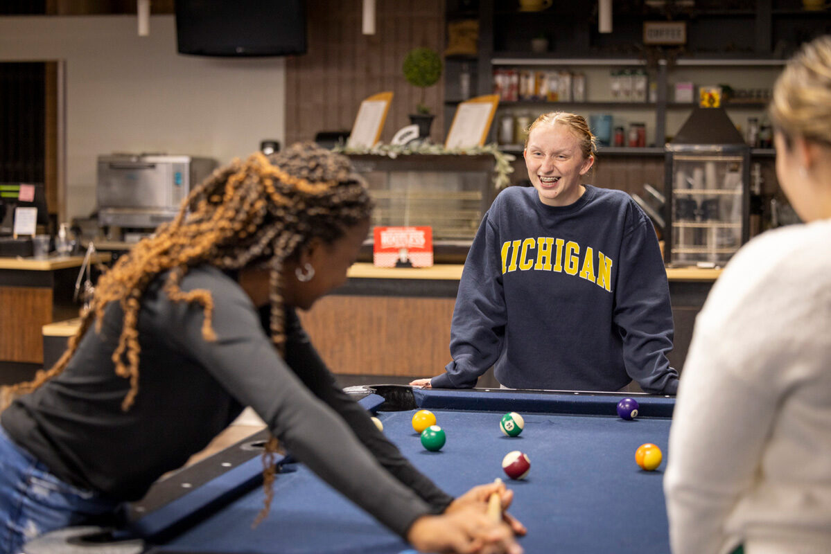 A group of young people playing pool and laughing together.