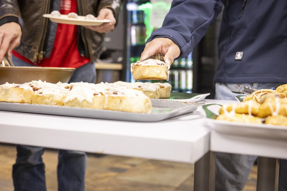 Close-up of someone picking a frosted pastry from a tray at a buffet.